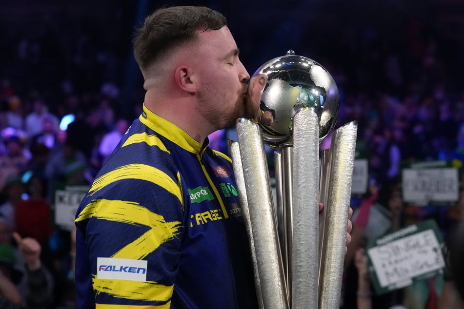 Poprvé po sobě: Luke Littler líbá trofej Sid‑Waddell.