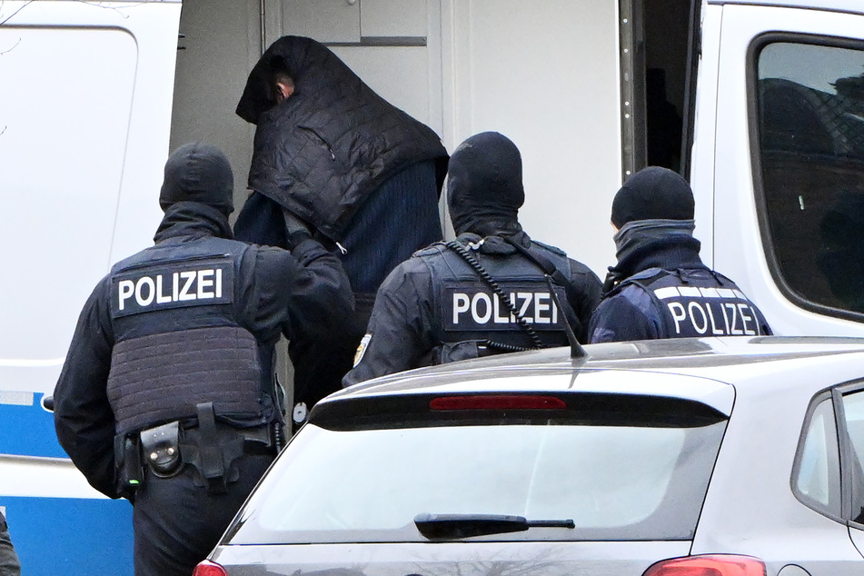Eine Person wird von Polizisten in Karlsruhe von einem Hubschrauber zu einem Auto geführt.