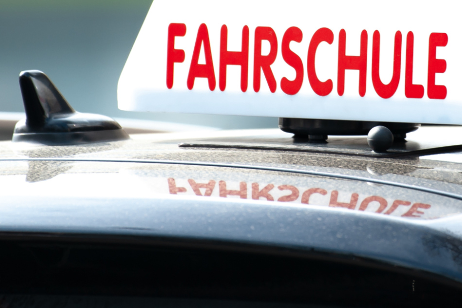Ein Schild mit der Aufschrift "Fahrschule" ist auf einem Fahrschulauto befestigt.