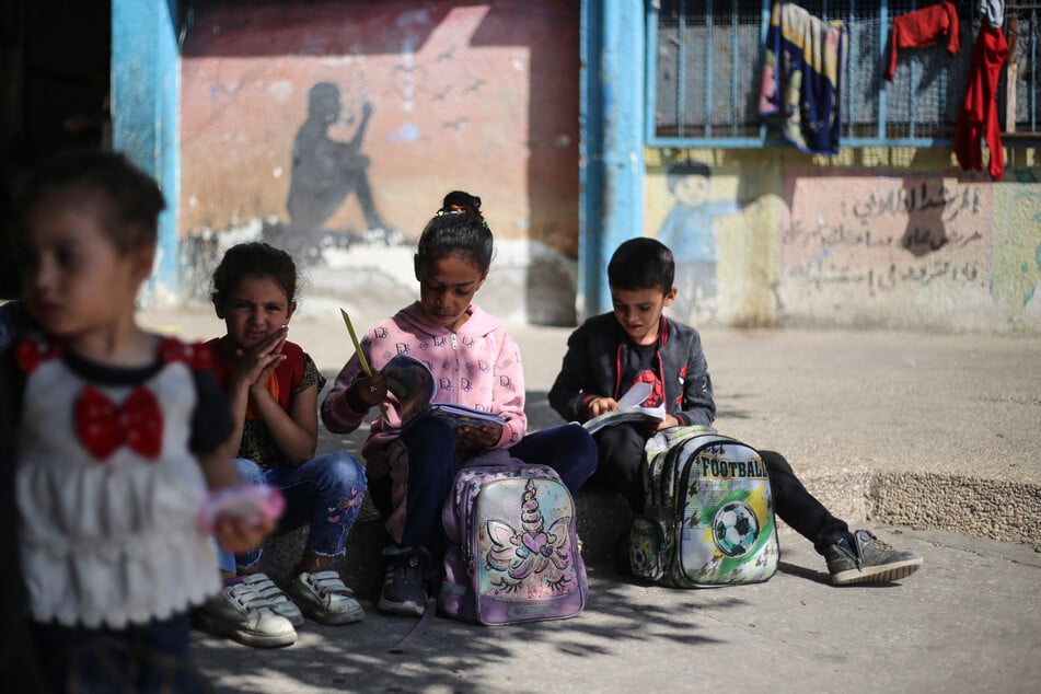 Palestinian children sit with their schoolbooks in the Nuseirat refugee camp, in the central Gaza Strip, on October 26, 2025.