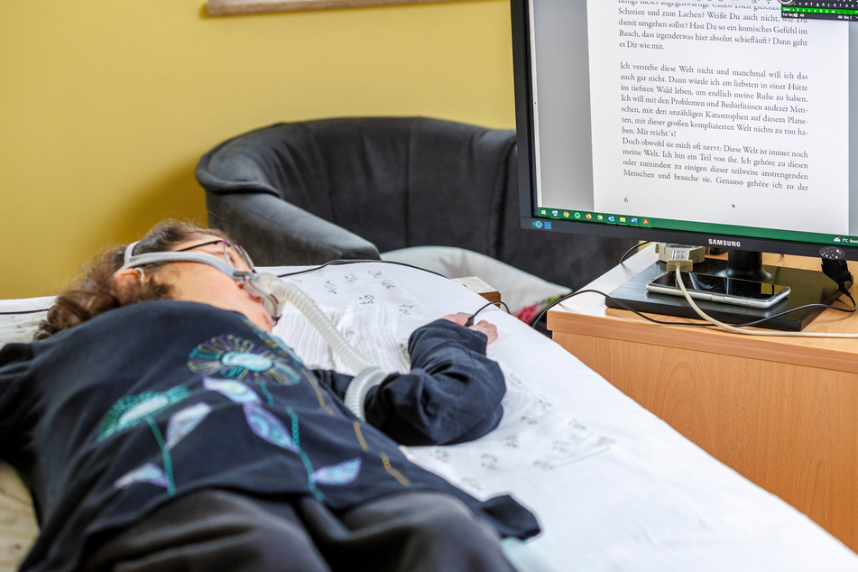 PC und Bildschirm stehen direkt am Bett der jungen Frau. Wenn sie Bücher lesen mag, hilft eine Maschine ihr beim Umblättern der Seiten.