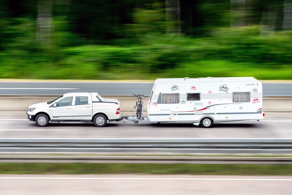 Ein Auto mit angehängtem Wohnwagen ist auf der A7 am Autobahnkreuz Hannover/Kirchhorst in Fahrtrichtung Süden unterwegs.