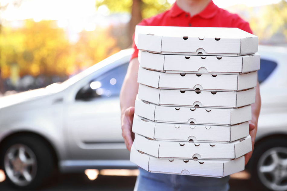 Ein Pizzabote hält mehrere Pizza-Kartons in der Hand (Symbolfoto).