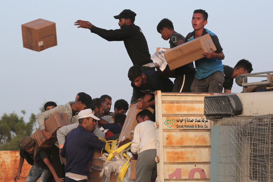 Palestinians carry boxes of humanitarian aid after rushing the trucks transporting the international aid from the US-built Trident Pier near Nuseirat in the central Gaza Strip on May 18, 2024, amid the ongoing conflict between Israel and the militant group Hamas.