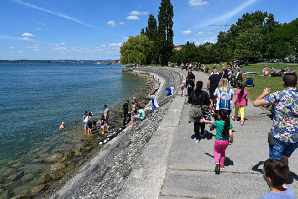 Meersburg: Ausflügler laufen an der Uferpromenade von Meersburg entlang.
