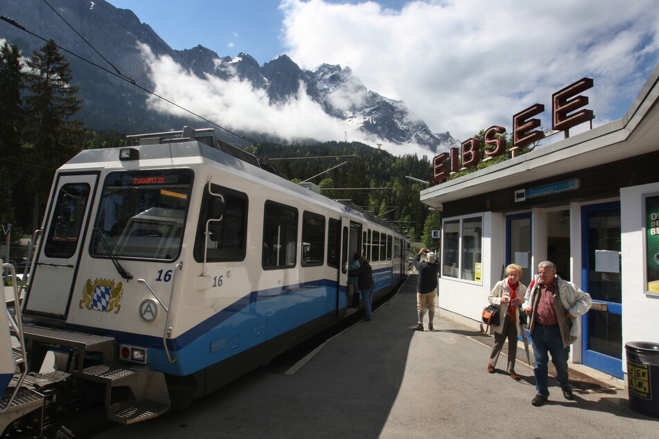 Ein Waggon der Zugspitzbahn am Bahnhof Eibsee vor der Kulisse der Zugspitze.