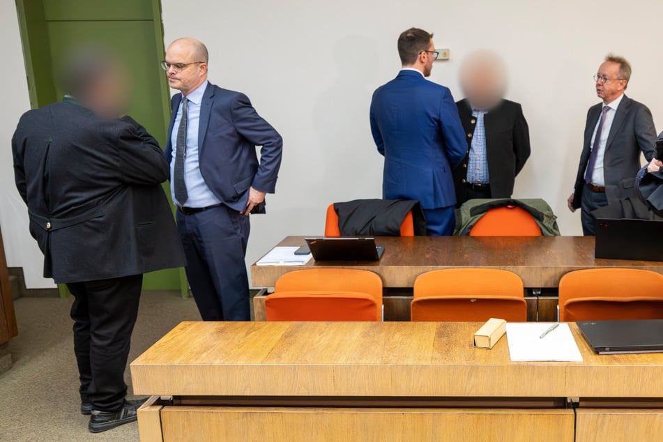 Die zwei beschuldigten Bahnmitarbeiter (links und 2. von rechts) stehen vor Prozessbeginn im Gerichtssaal des Landgerichts München II.