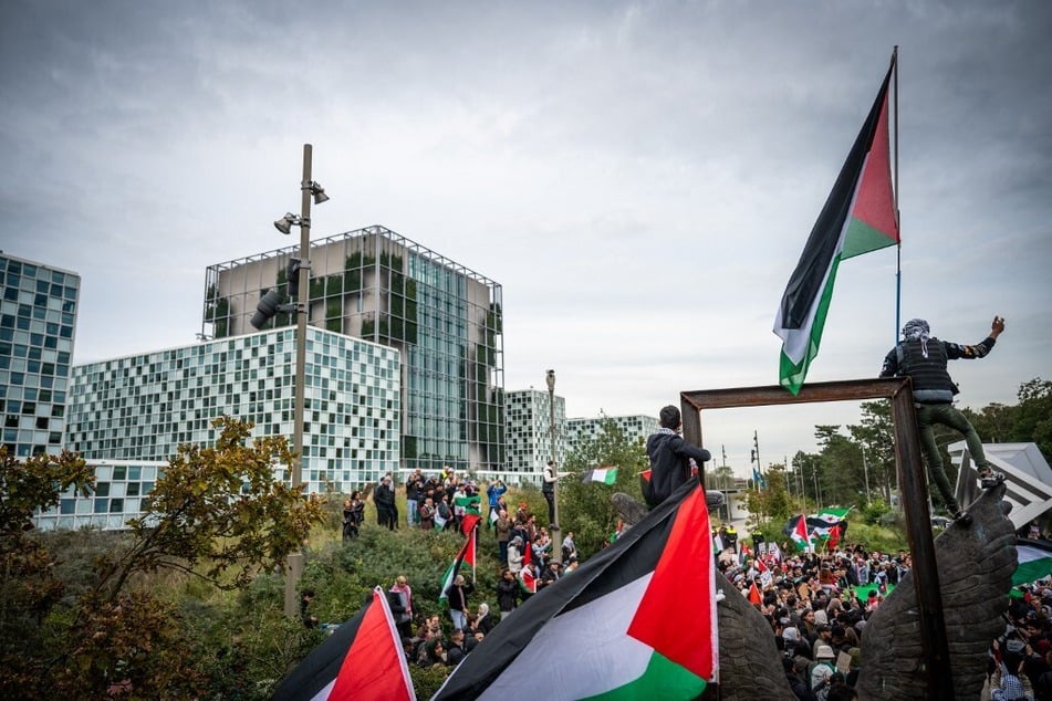 Protestors raise Palestinian flags during a Gaza solidarity demonstration in front of the International Criminal Court in the Hague, Netherlands.