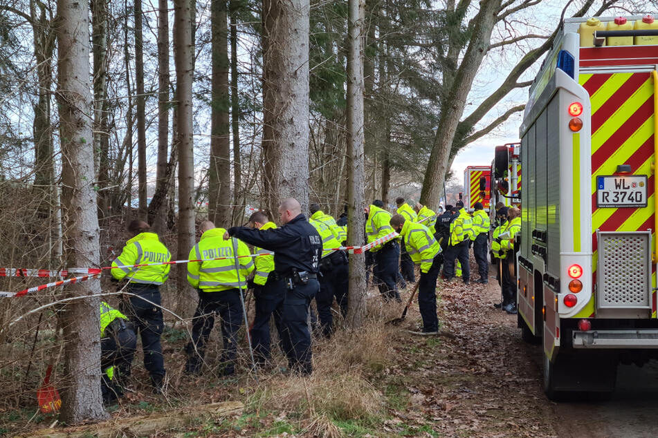 Polizisten durchkämmen das Waldstück, in dem das Erddepot gefunden wurde.