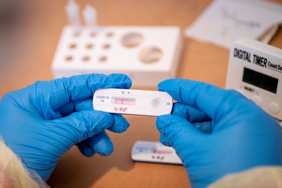 Ein Sanitäter hält vor dem Tempodrom einen Testträger eines Corona-Schnelltests in der Hand.