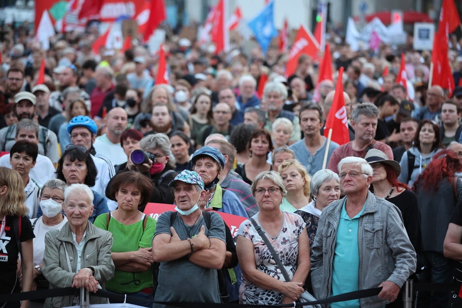 Teilnehmer einer Linken-Kundgebung lauschen den Redebeiträgen auf dem Augustusplatz.