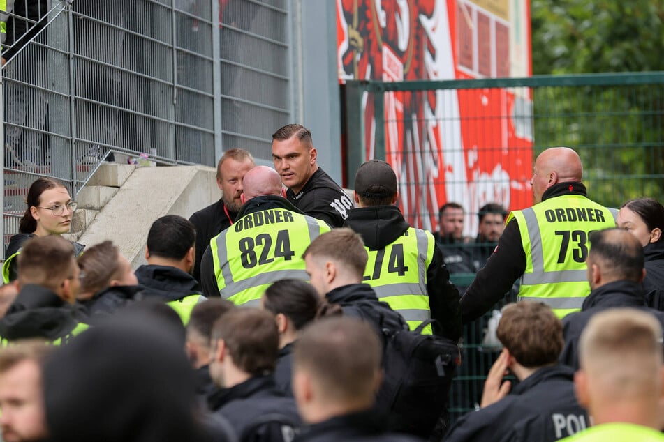 Das Sicherheitspersonal unterbindet den Überraschungsangriff von FCE-Fans auf den Gästeblock nach Abpfiff.