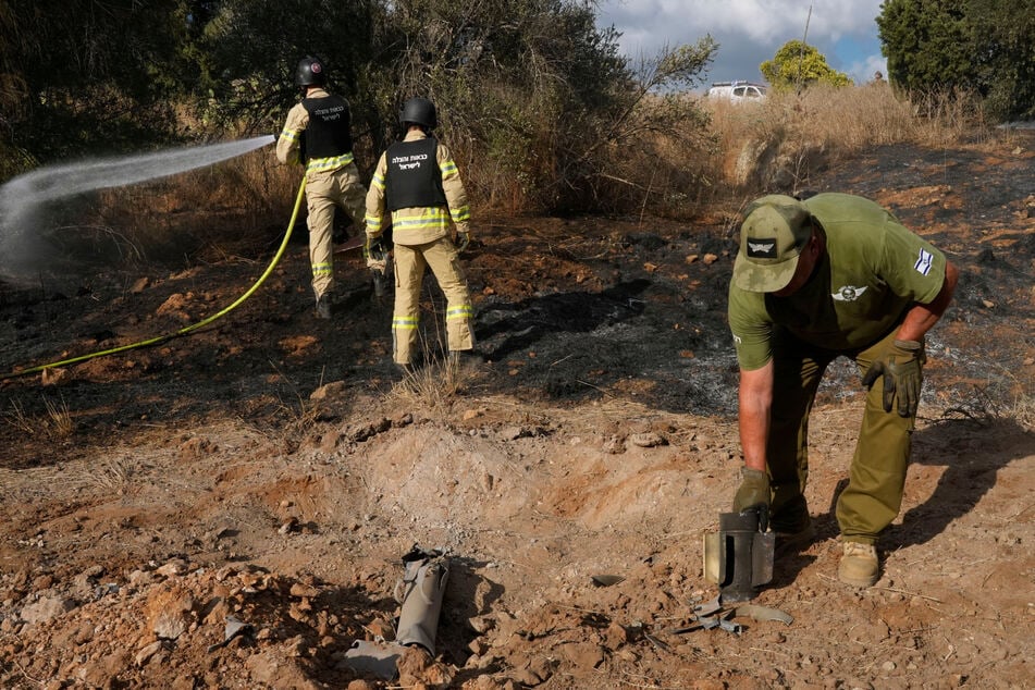 Israelische Feuerwehrleute und ein Bombenentschärfungsteam der Polizei arbeiten in der Nähe von Nahariya im Norden Israels an einer Stelle, die von einer aus dem Libanon abgefeuerten Rakete getroffen wurde.