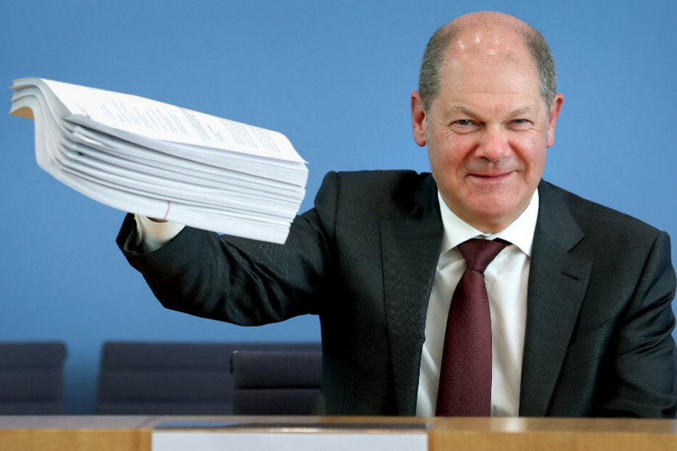 Olaf Scholz (61, SPD), Bundesfinanzminister, gibt eine Pressekonferenz zum Hilfspaket der Bundesregierung für Betroffene der Corona-Krise und hält einen Stapel Unterlagen in die Höhe.