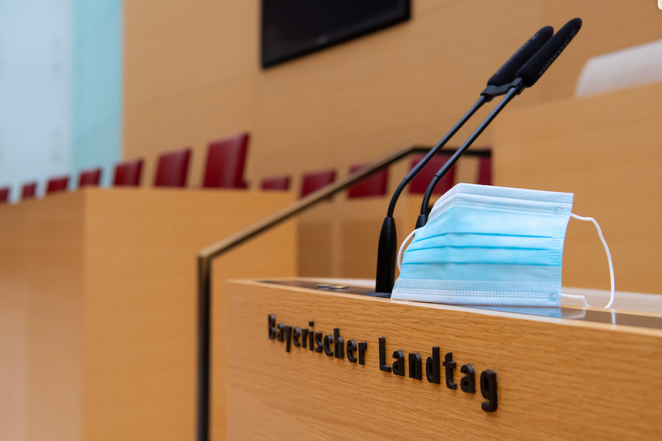 Ein Mund-Nase-Schutz befindet sich im Plenarsaal im bayerischen Landtag neben Mikrofonen.