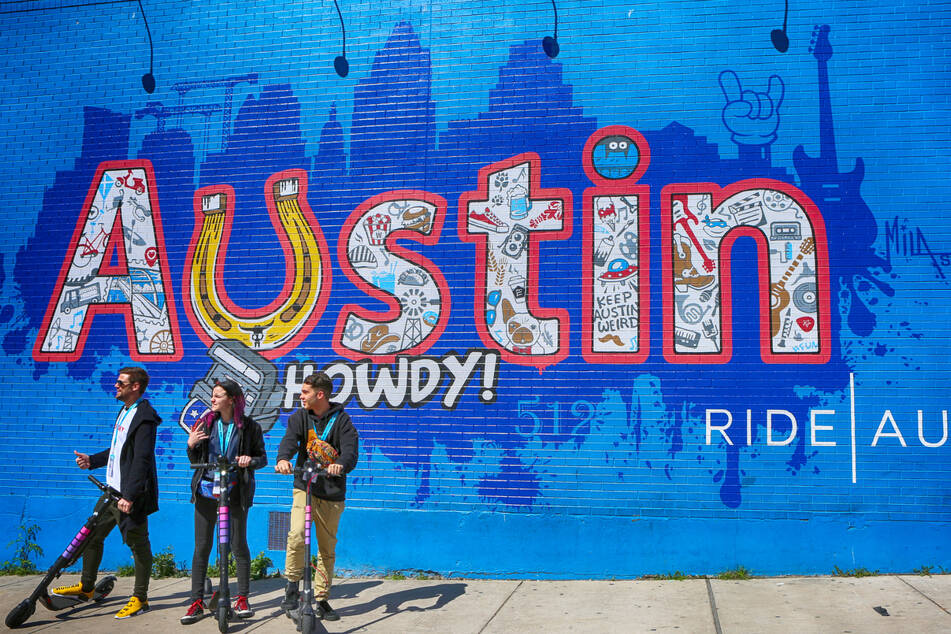 Auf Elektrorollern stehen Mitglieder des "South by Southwest"-Festivals vor einem Graffiti in Austin, Texas. Das Festival wird voraussichtlich kommenden Sommer in Berlin stattfinden.