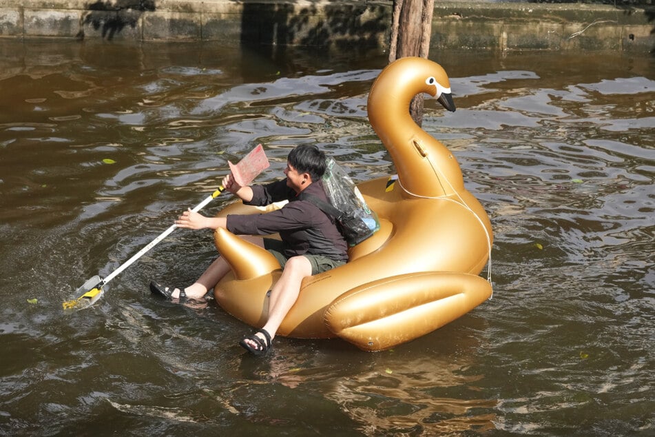 Ein Mann paddelt nach tagelangen Regenfällen mit einem Schlauchboot durch eine überflutete Straße.