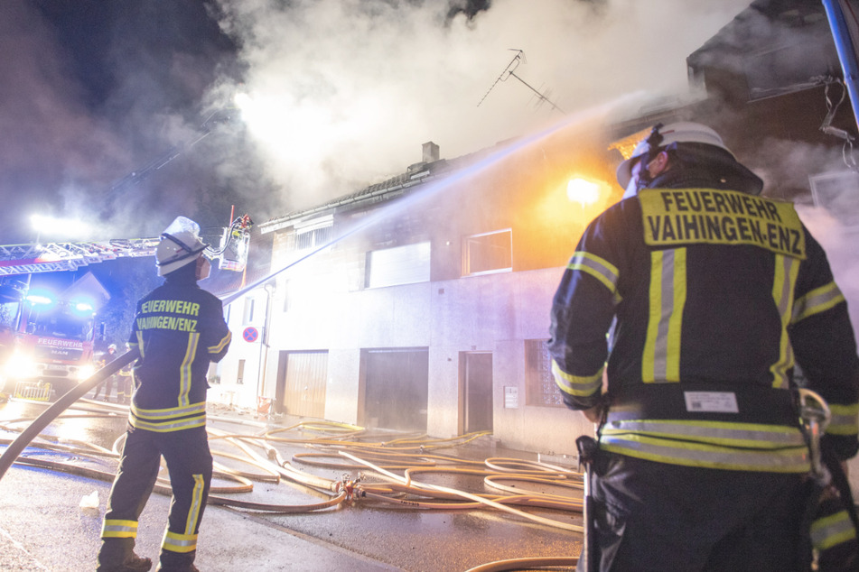 Feuerwehrleute löschen mit einem Schlauch das Mehrfamilienhaus.