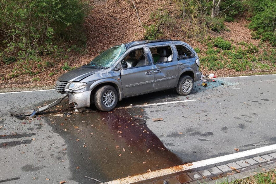Der Chrysler steht stark beschädigt auf der Straße.