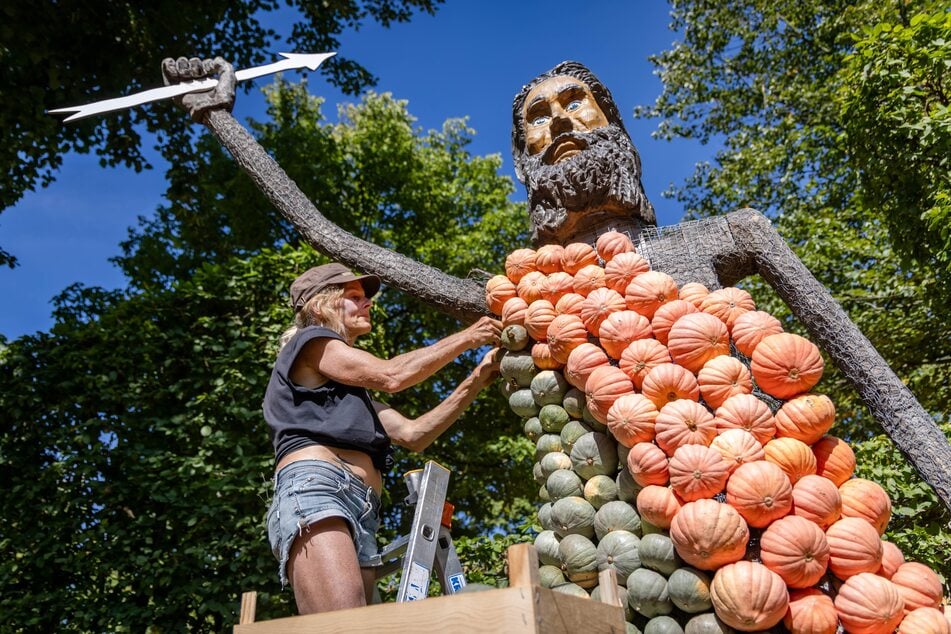 "Jucker Farm"-Mitarbeiterin Gesine Geiger montiert Kürbisse an eine Figur.