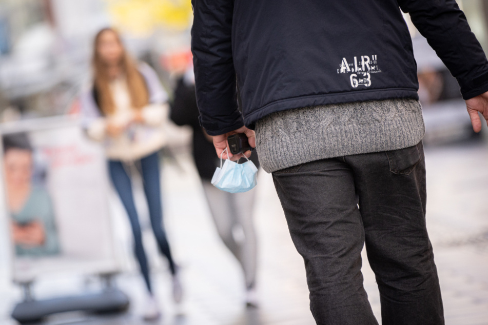 Da ist der Mund-Nase-Schutz meist falsch: Ein Mann trägt ihn in Delmenhorst in der Hand durch die Fußgängerzone.