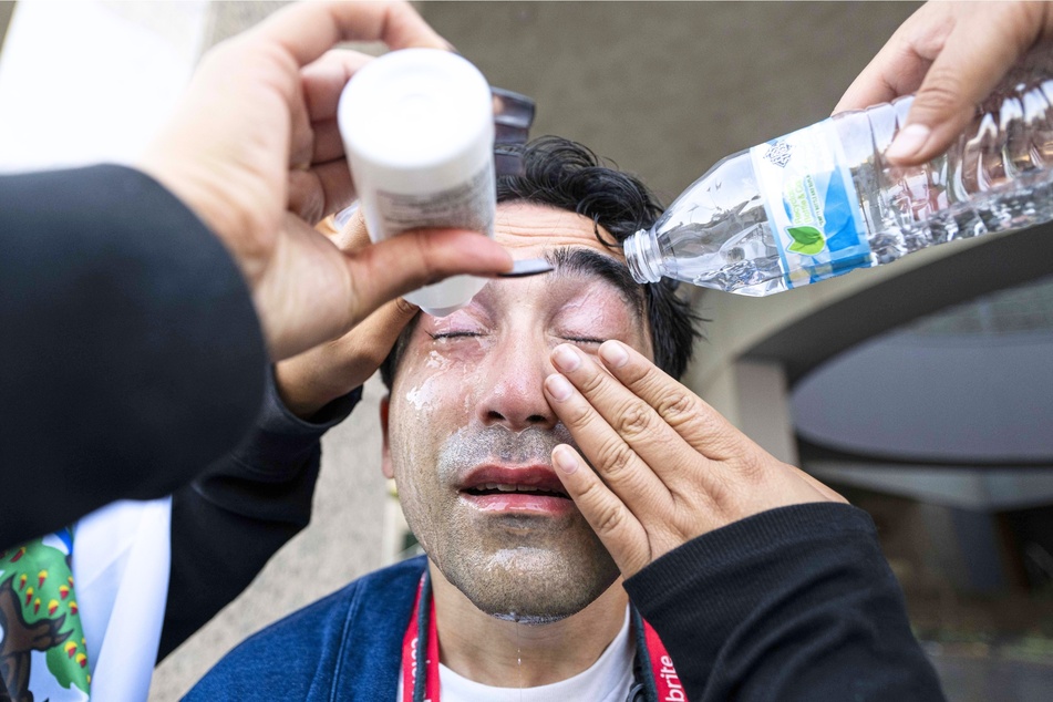 A reporter has his eyes flushed after getting in the cross fire of pepper spray shot by a federal agent during a protest in Los Angeles, California on June 06, 2025.