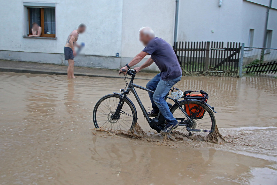 Ein Fahrradfahrer kämpft sich durch eine überflutete Straße in Meerane.