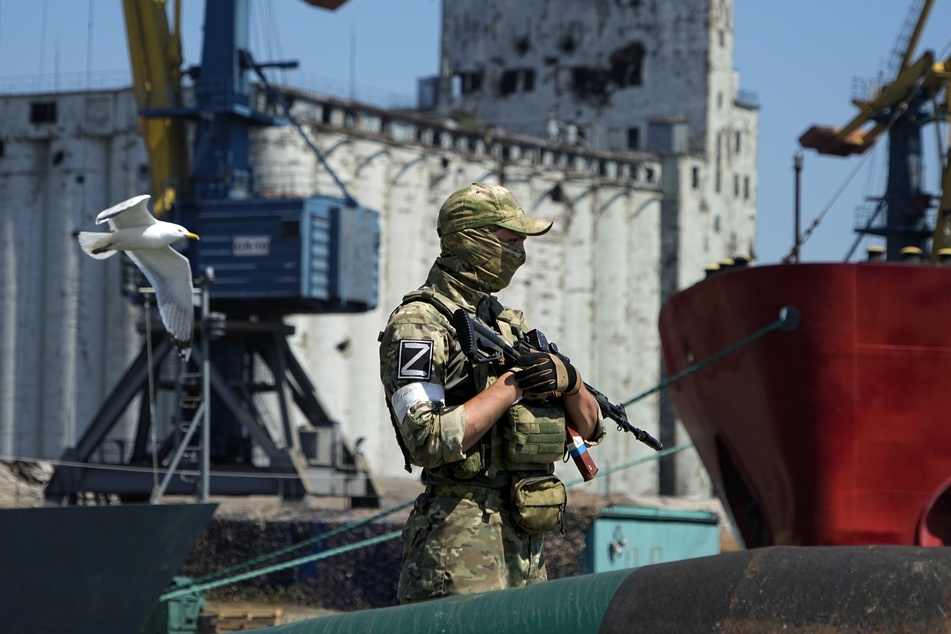 Ein russischer Soldat bewacht einen Pier mit einem Getreidespeicher im Hintergrund auf dem Gelände des Seehafens von Mariupol, der nach schweren Kämpfen wieder in Betrieb genommen wurde.