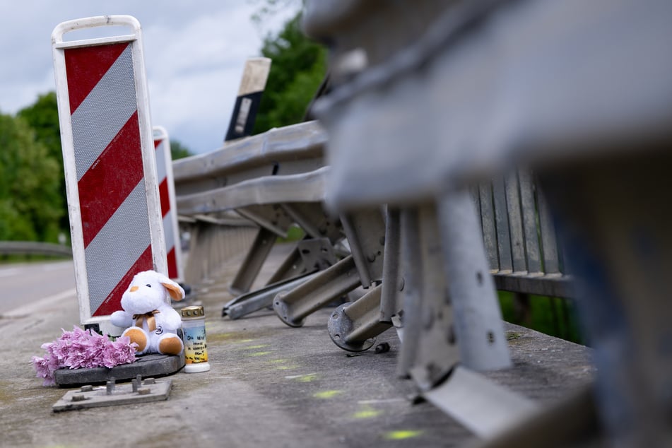Kerzen und Blumen und ein Stofftier stehen nach dem tragischen Zusammenstoß an der Unfallstelle.