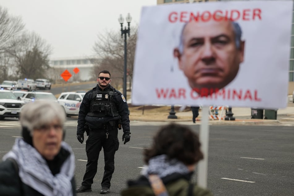 Protesters raise a sign depicting Israeli Prime Minister Benjamin Netanyahu along with the message "Genocider, War Criminal" outside the Donald J. Trump Institute of Peace in Washington DC on February 19, 2026.