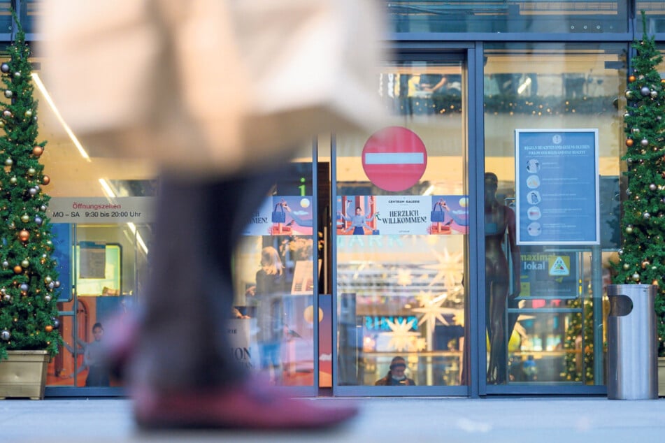 Ein Passant geht mit einer Papiertüte auf der Einkaufsstraße Prager Straße entlang.