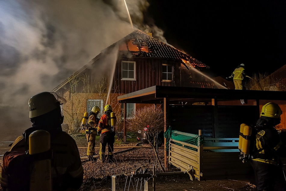 Die Feuerwehrleute löschen das brennende Dach.