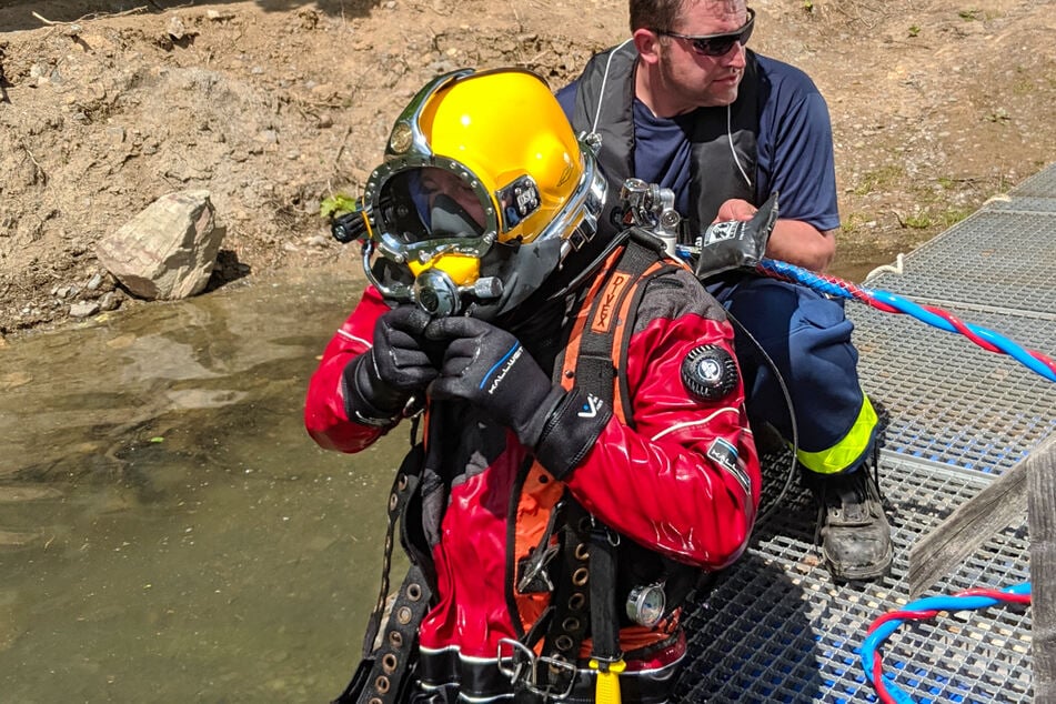 Bergungstaucher im Einsatz unter Wasser mit Taucheranzug und Spezialwerkzeug.