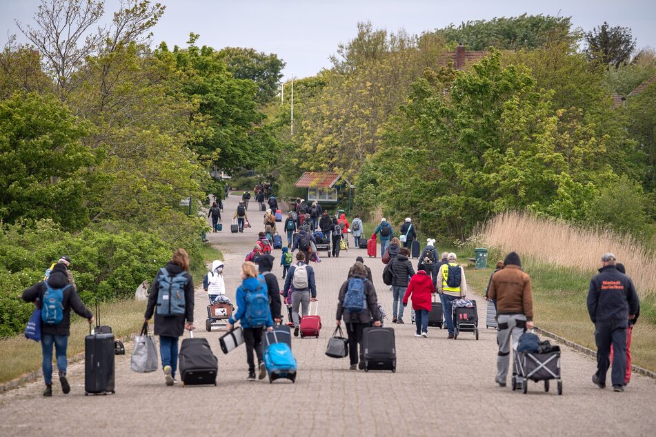 Spiekeroog: Touristen mit Koffern laufen über die Insel.