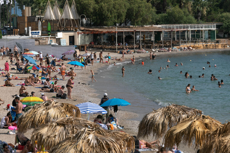 Athen: Menschen genießen das warme Wetter am Strand und baden im Meer.