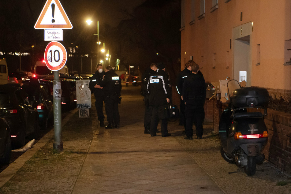 Polizisten stehen an einem Haus in Schöneberg.