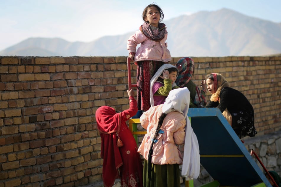 Kinder spielen in Afghanistan in einem Lager für Vertriebene an einer Rutsche.