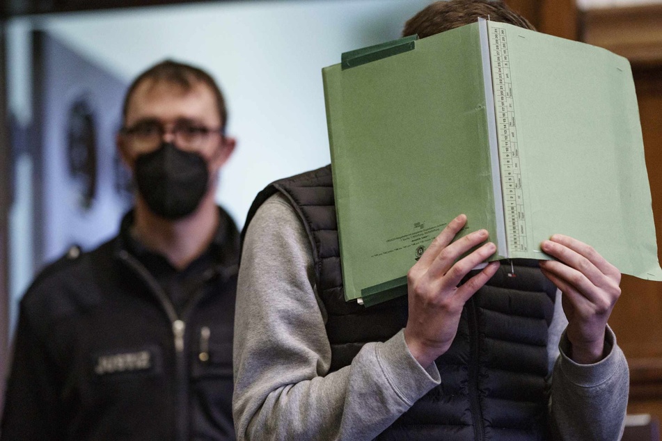 Der 20-jährige Angeklagte im Prozess wegen Totschlags wird von einem Mitarbeiter der Justiz zur Urteilsverkündung in den Gerichtssaal geführt.