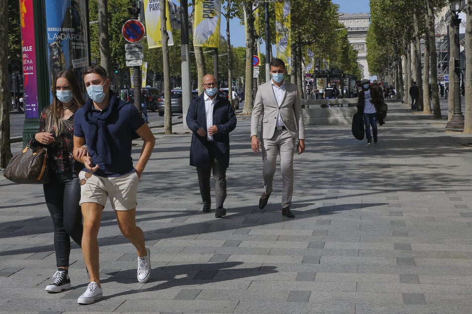Paris: Passanten tragen auf der Champs-Elysees Mundschutze.