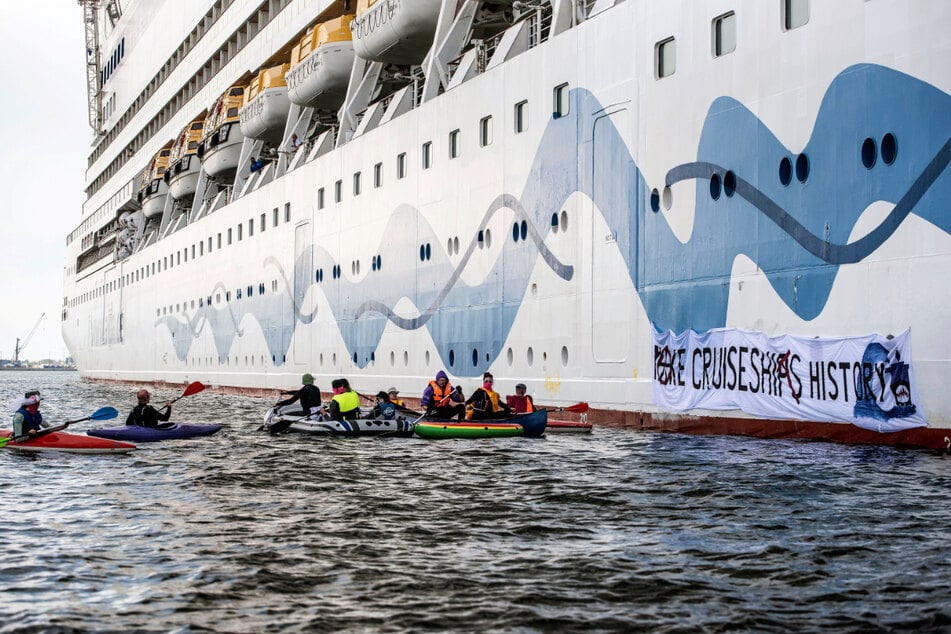 Mit kleinen Booten und Kanus halten die Klimaaktivisten das riesige Kreuzfahrtschiff auf.