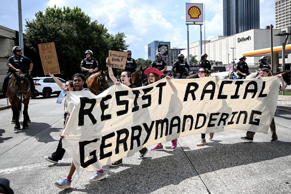 Mounted police officers watch as a protesters hold a banner reading "Resist Racial Gerrymandering" while marching during a Labor Day "Workers Over Billionaires" rally in Houston, Texas, on September 1, 2025.