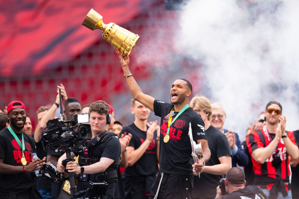 Bayer-Abwehrchef und -Kapitän Jonathan Tah (28) präsentiert den Fans im Stadion die gewonnenen Trophäen.