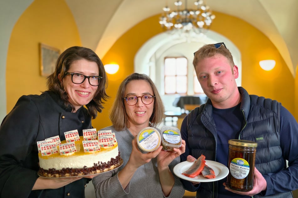 Konditormeisterin Karin Kowanda (45, l.) bringt eine Jubiläumstorte mit. Projektleiterin Annekathrin Haufe (42) von C3 und Niclas-Maurice Becher (22) zeigen Fischspezialitäten aus Zschorlau.
