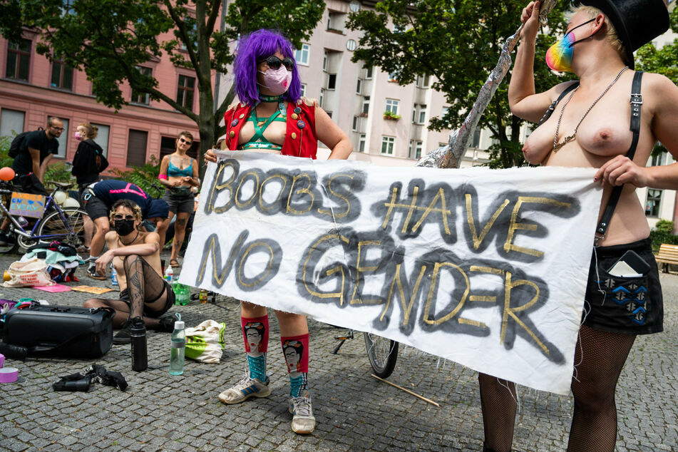 Teilnehmer einer Fahrraddemo unter dem Motto "No Nipple is free until all Nipples are free!" tragen ein Transparent mit der Aufschrift "boobs have no gender".