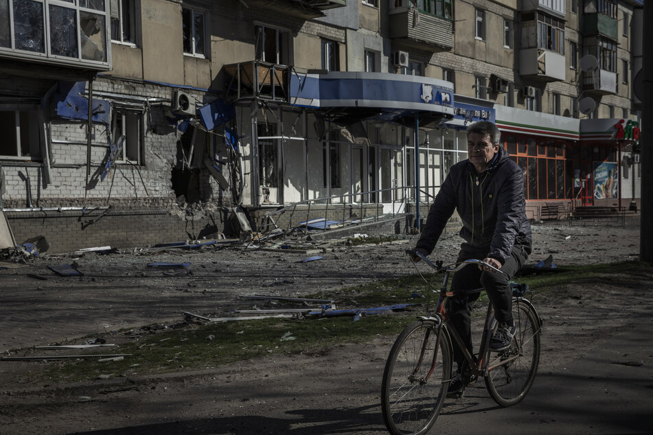 Ein Mann fährt mit einem Fahrrad an einem Wohnhaus in Sjewjerodonezk vorbei, das durch einen früheren russischen Angriff beschädigt wurde. Die blutigen Straßenkämpfe in der Großstadt dauerten an.