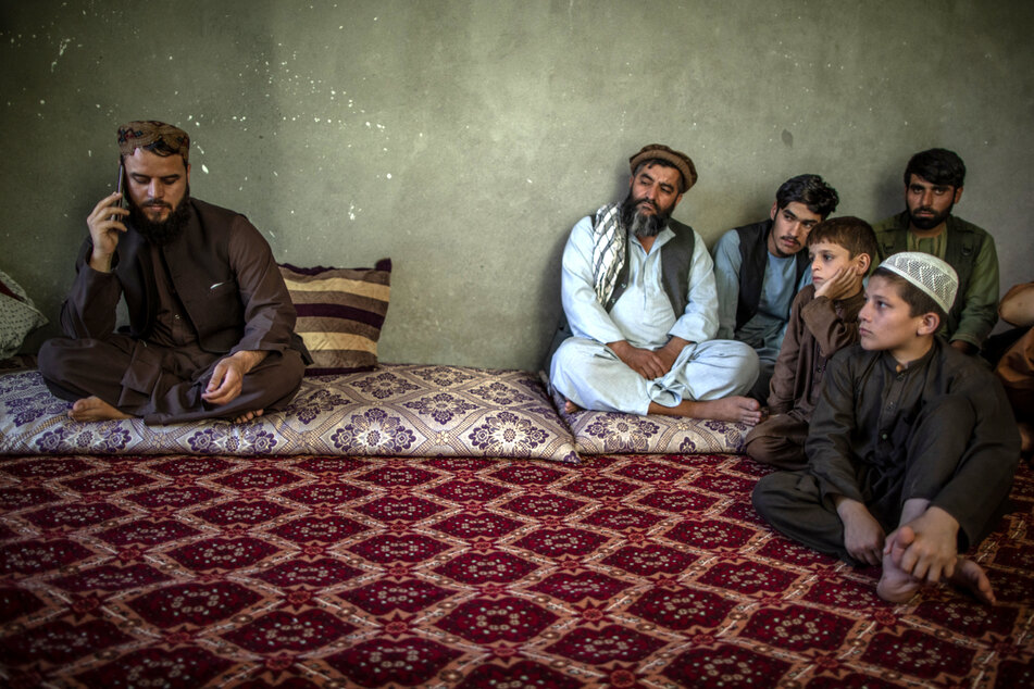 Matiullah Ruhani (l.), Sprecher der Taliban für Kundus, wird während eines Telefonats von anderen Taliban und Kindern beobachtet.