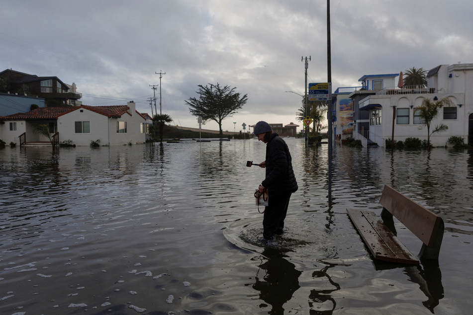 A resident walks along a flooded street, after "atmospheric river" rainstorms slammed northern California, in the coastal town of Aptos.