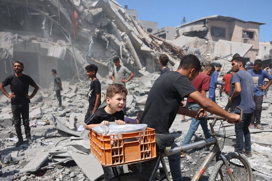Palestinians walk past a destroyed building after an Israeli strike on Al-Nassr Street in Gaza City on September 12, 2025.