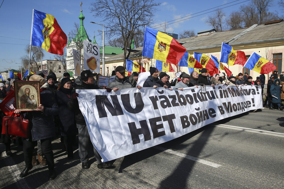 Menschen marschieren mit einem Transparent, auf dem "Nein zum Krieg in Moldau" steht, durch die Straßen von Chisinau.