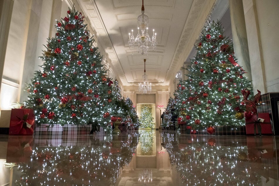 The Cross Hall, which connects the State Dining Room and the East Room, is decorated with festive Christmas trees.